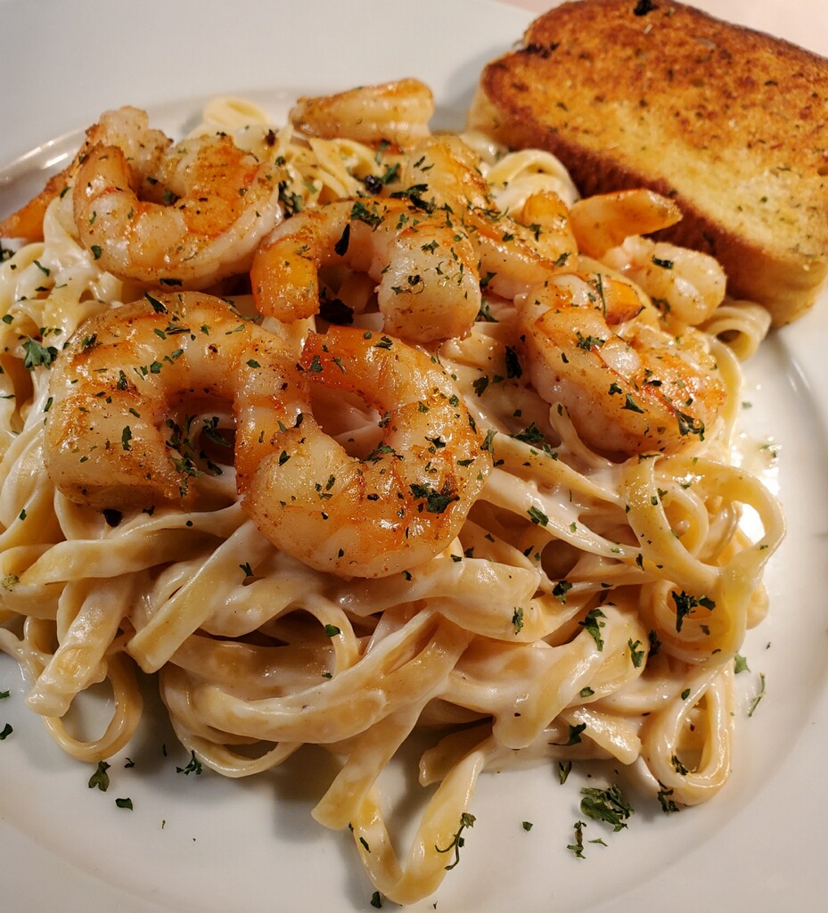 Plated shrimp alfredo with fettuccine and fresh herbs